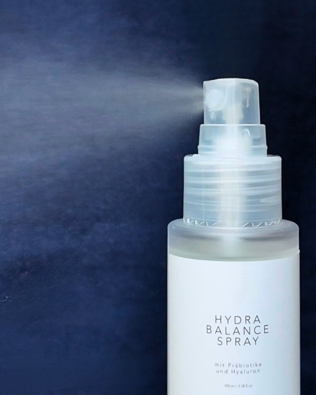 Nahaufnahme von Hydra Balance Spray mit Sprühnebel vor dunkelblauem Hintergrund
